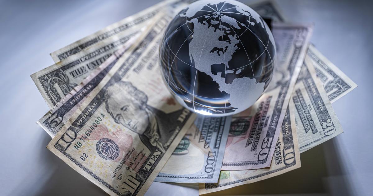 A glass globe sits atop a pile of American bills, symbolizing the impact of regulation on economic freedom in business.